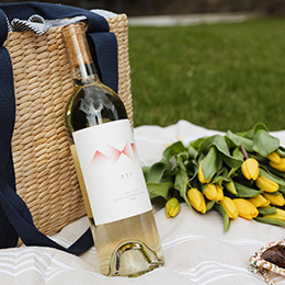 Bottle of AXR Ganzin Sauvignon Blanc and yellow tulipc at an outdoor picnic