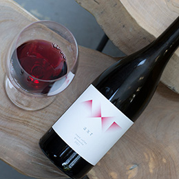 Bottle and glass of AXR 2021 Grenache on a wood slab